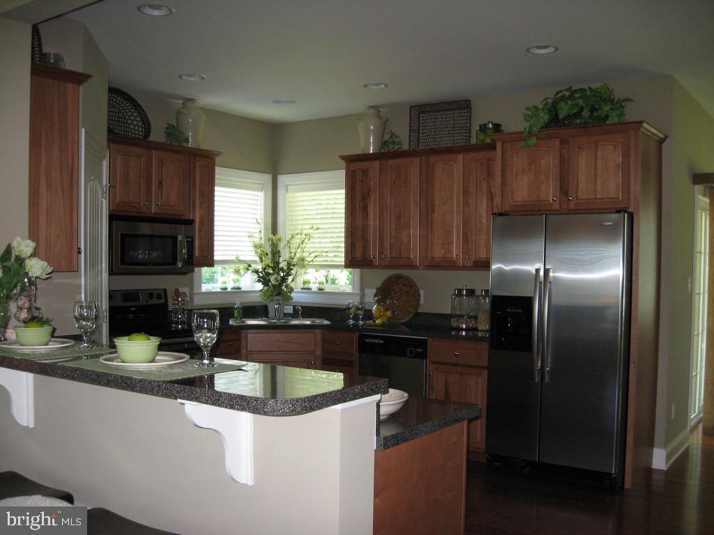139 Baneberry Lane, Unit 15 Lititz, PA 17543 - Photo 4 of 9 a kitchen with granite countertop a refrigerator a stove a sink a counter space and cabinets