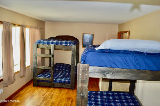 a bedroom with a bed and dresser with wooden floor