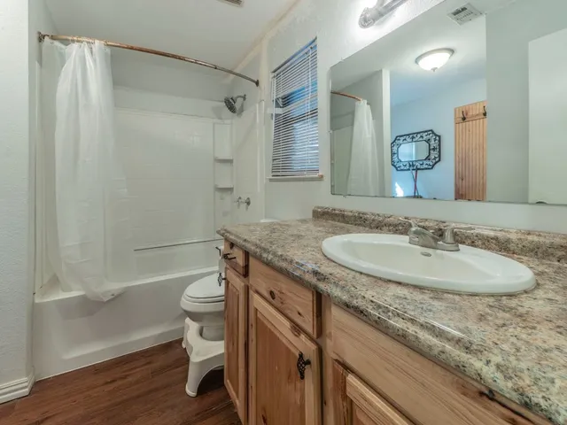 a bathroom with a granite countertop sink toilet and shower