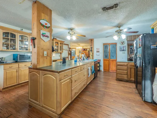 a large white kitchen with stainless steel appliances kitchen island granite countertop a refrigerator a stove and a sink with wooden floor