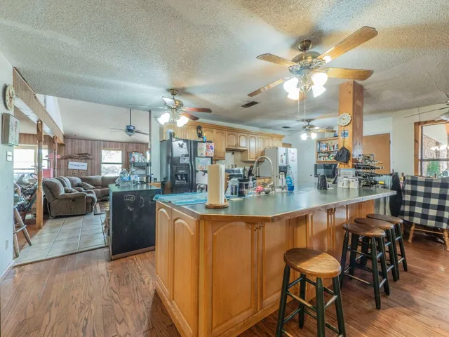 a kitchen with stainless steel appliances kitchen island granite countertop a table chairs and a refrigerator