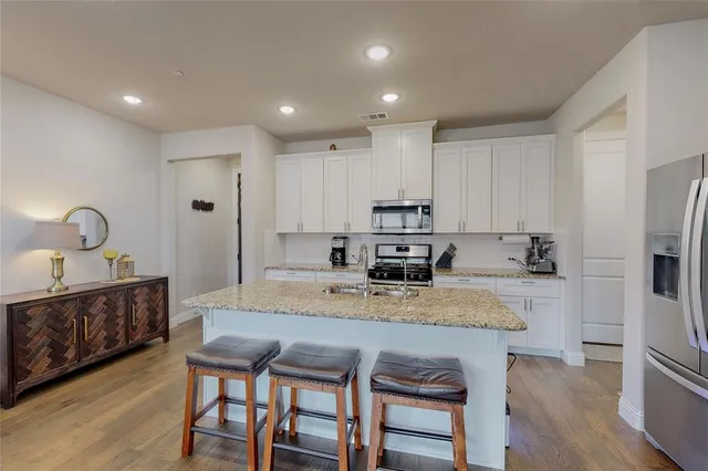 a kitchen with stainless steel appliances granite countertop a table chairs sink refrigerator and microwave