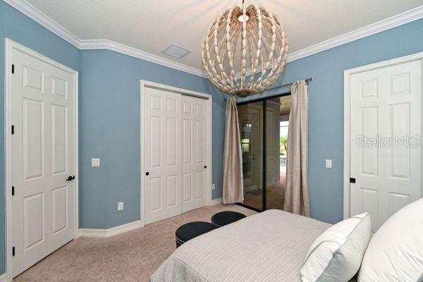 5507 Arnie Loop Lakewood Ranch, FL 34211 - Photo 22 of 68 a bedroom with a large bed and a chandelier