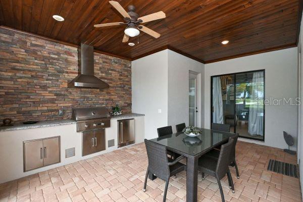 5507 Arnie Loop Lakewood Ranch, FL 34211 - Photo 43 of 68 a kitchen with stainless steel appliances kitchen island granite countertop a stove a refrigerator a dining table and chairs with wooden floor