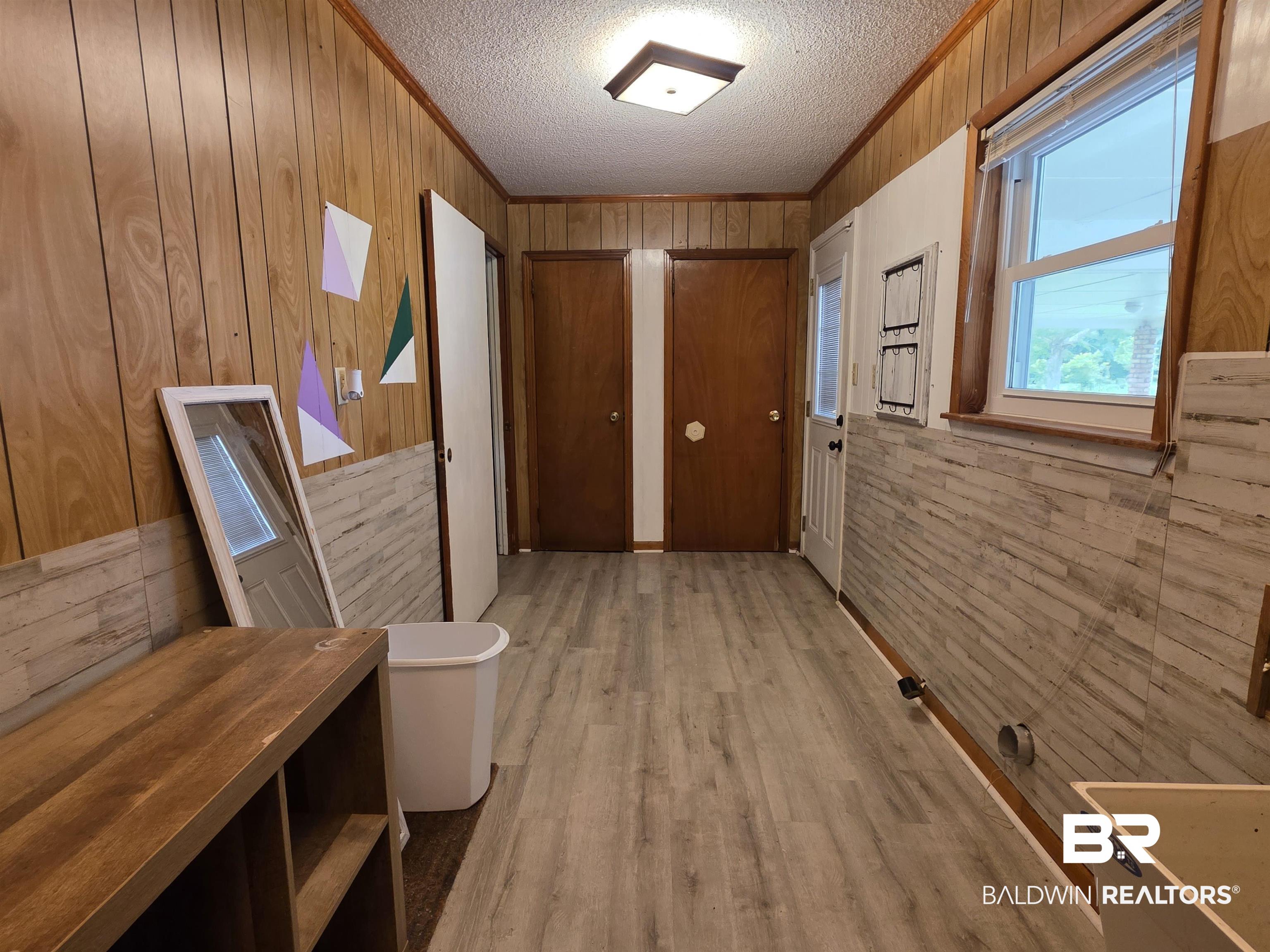 558 Stanton Road Atmore, AL 36502 - Photo 18 of 29 Spacious utility area featuring wood-finish wall paneling, a light wood-finish accent wall, and wood-finish flooring