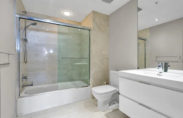 a kitchen with stainless steel appliances kitchen island granite countertop a refrigerator a stove and white cabinets with wooden floor