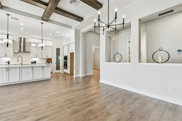 a kitchen with stainless steel appliances a refrigerator a sink dishwasher a oven and white cabinets with wooden floor