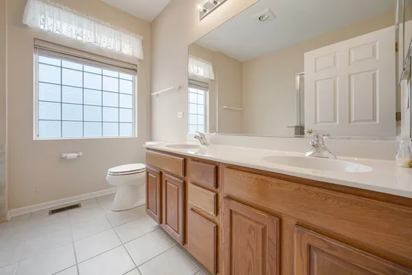 a bathroom with a double vanity sink a toilet and a tub