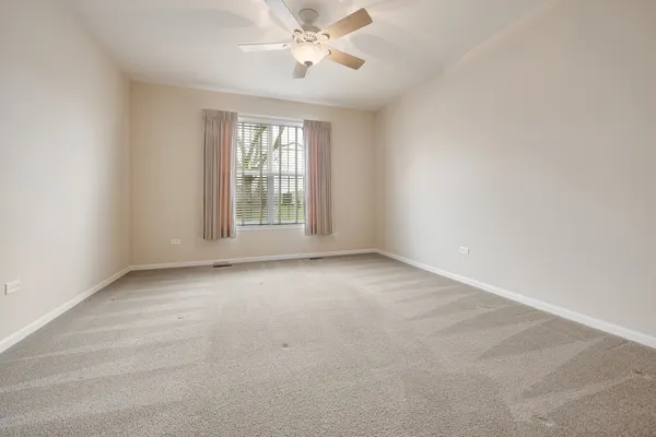 an empty room with chandelier fan and windows