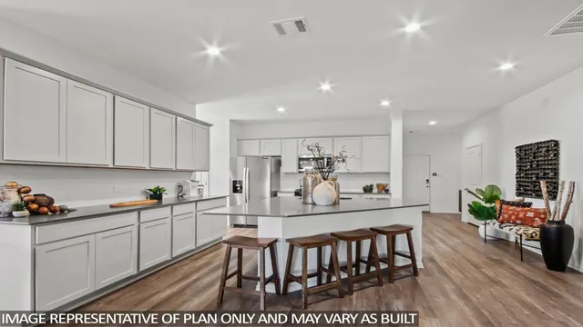 a kitchen with stainless steel appliances kitchen island granite countertop a dining table chairs sink and white cabinets