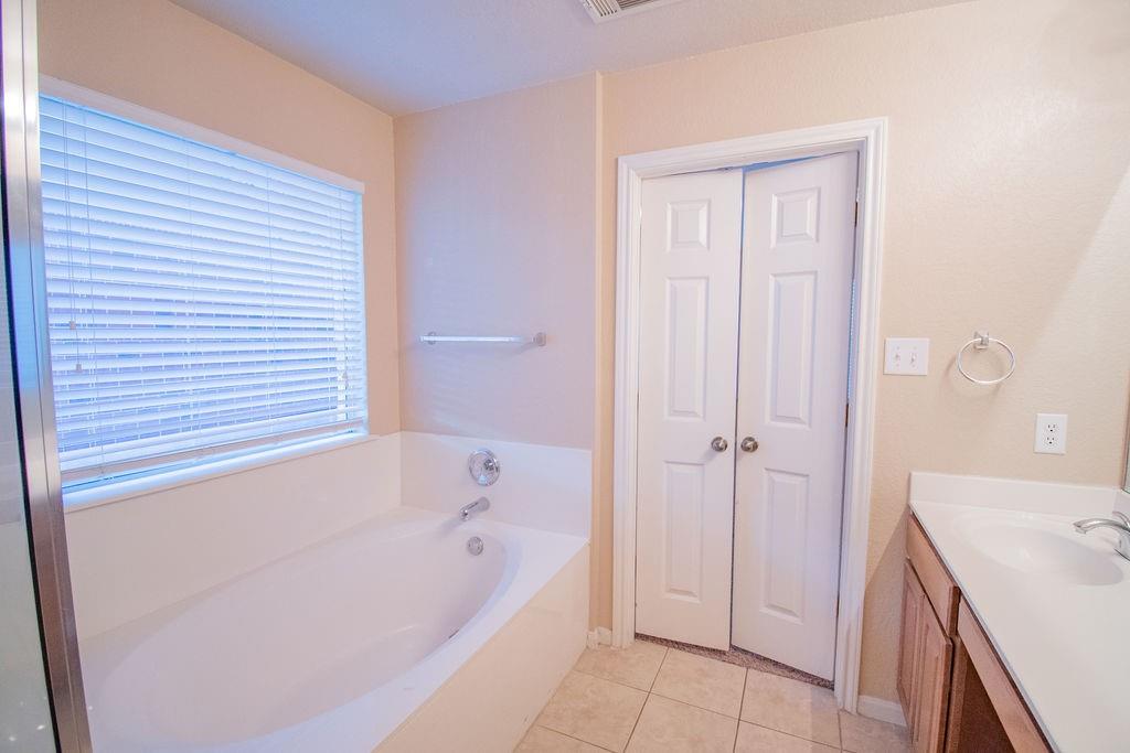 312 Pheasant Ridge Drive Round Rock, TX 78665 - Photo 22 of 34 Relax in this tranquil bathing space, featuring a built-in tub with a window view and accessible vanity.