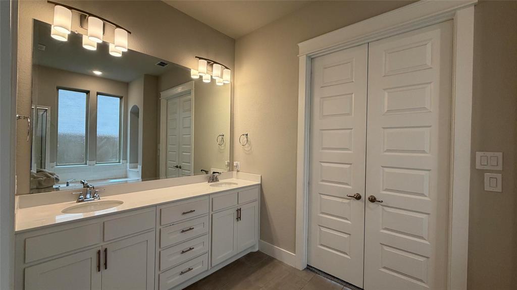 912 Fallbrook Avenue Denton, TX 76210 - Photo 12 of 26 a spacious bathroom with a double vanity sink a mirror and a shower