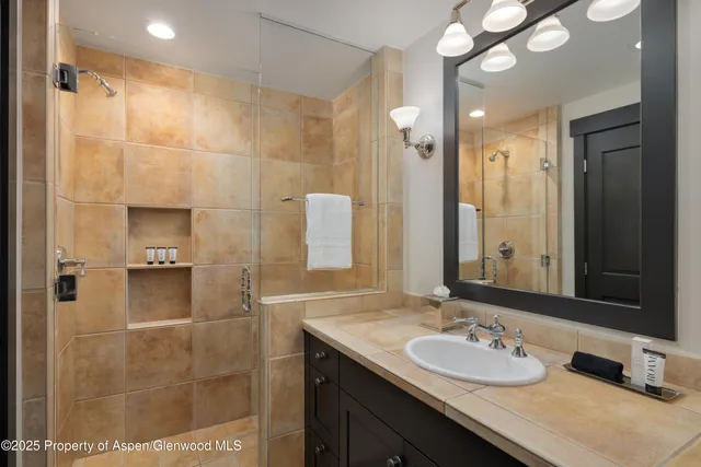 a bathroom with a granite countertop sink a mirror and a shower