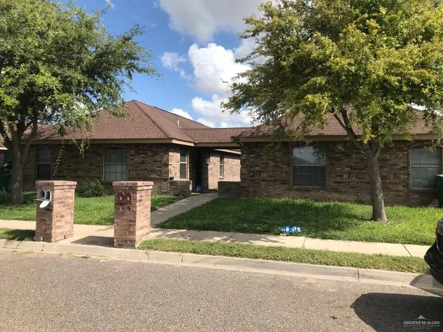 a front view of a house with a garden and tree