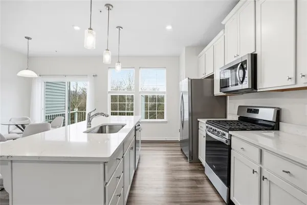 a kitchen with stainless steel appliances granite countertop a sink a stove and a wooden floors