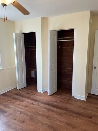 a view of an empty room with wooden floor and closet
