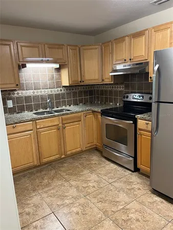 a kitchen with granite countertop a sink stainless steel appliances and cabinets