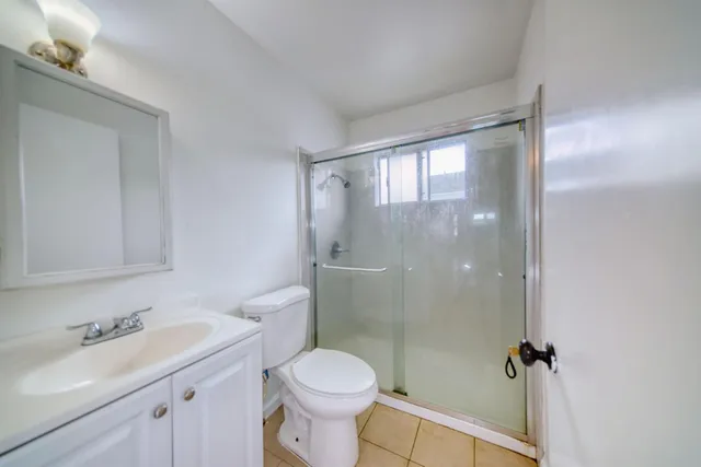 a bathroom with a shower sink vanity mirror and toilet