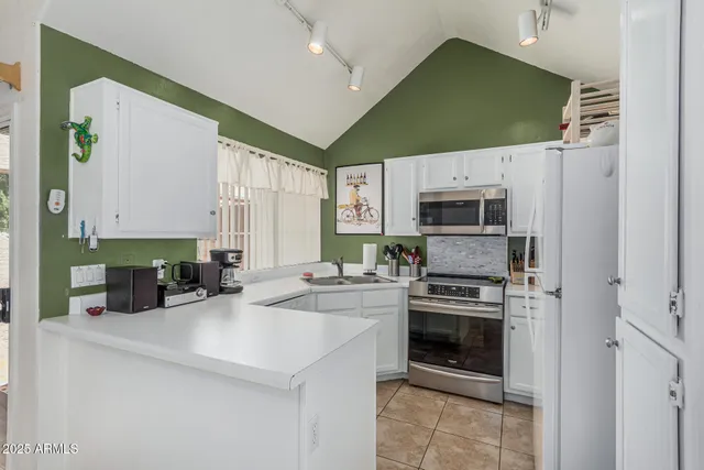 a kitchen with white cabinets a sink and a large window