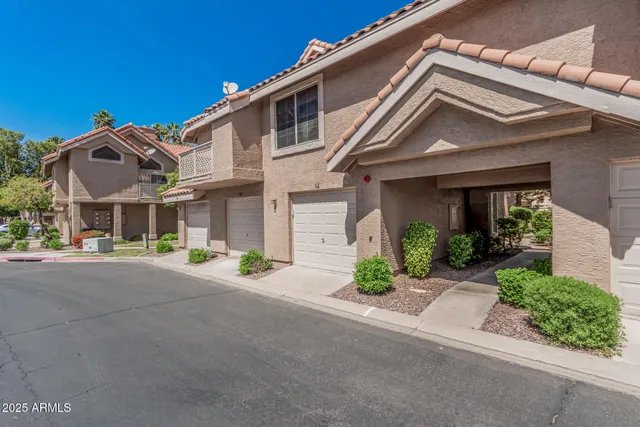 a view of a white house with a large windows and table and chairs in a yard