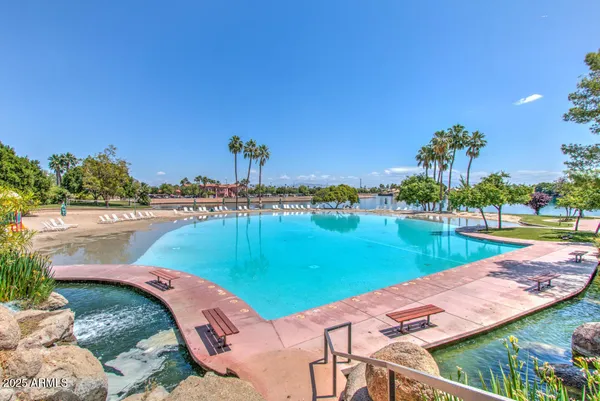 a view of a swimming pool with lawn chairs under an umbrella