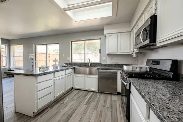 a kitchen with granite countertop cabinets stainless steel appliances a sink and window