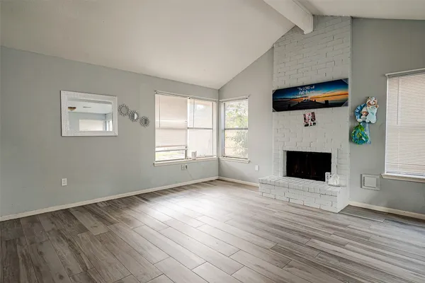 an empty room with windows fireplace and wooden floor