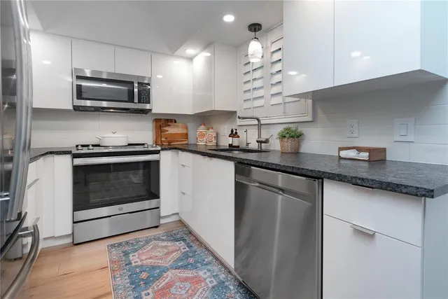 a kitchen with granite countertop a sink dishwasher a stove and a microwave oven with cabinets