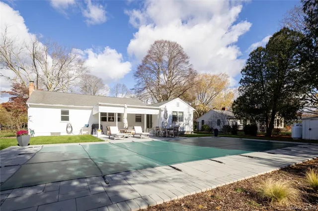 a view of a white house with a big yard and large trees