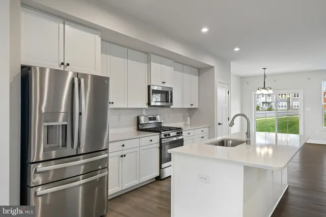 a kitchen with stainless steel appliances a refrigerator sink and white cabinets