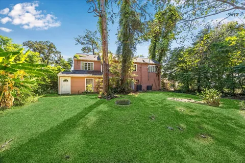 a view of a house with a big yard and large trees