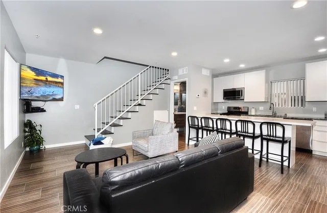 a living room with furniture and kitchen view with wooden floor