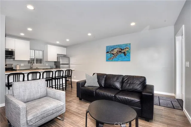 a living room with furniture and a dining table with wooden floor
