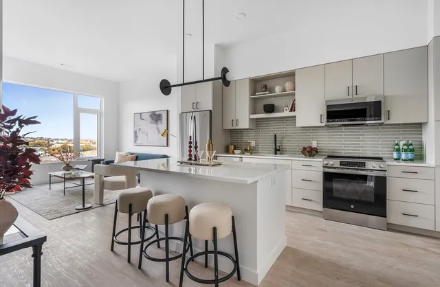 a kitchen with stainless steel appliances granite countertop a stove top oven a sink a dining table and chairs with wooden floor