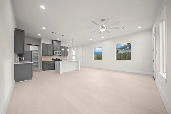 a view of an empty room with kitchen and kitchen view