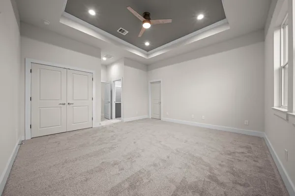 an empty room with chandelier fan and windows
