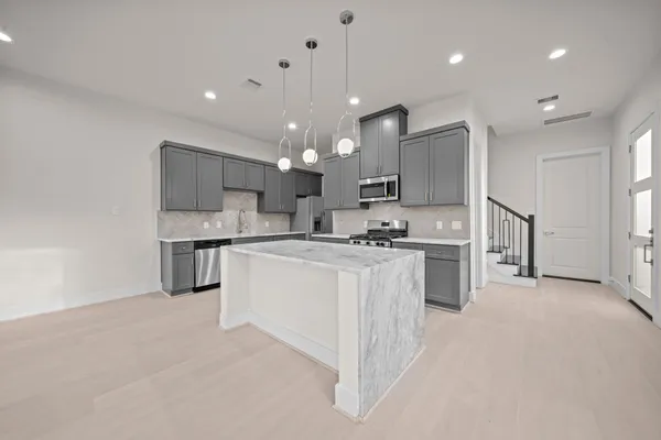 a kitchen with stainless steel appliances kitchen island a sink a refrigerator and a stove