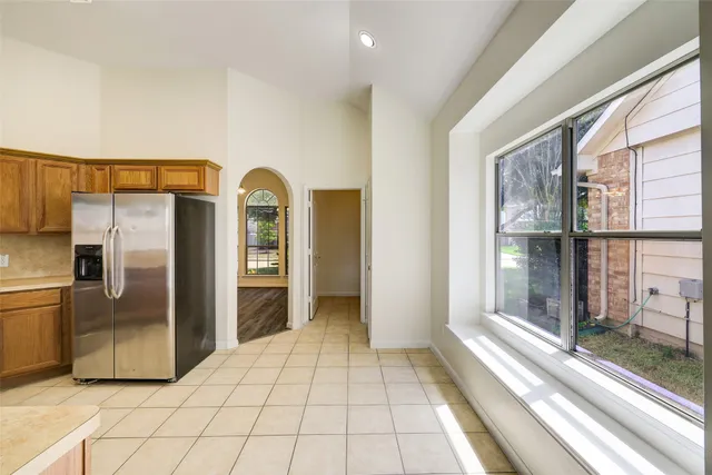 a view of a refrigerator in kitchen and an empty room