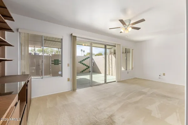 a view of an empty room with cabinet and a ceiling fan