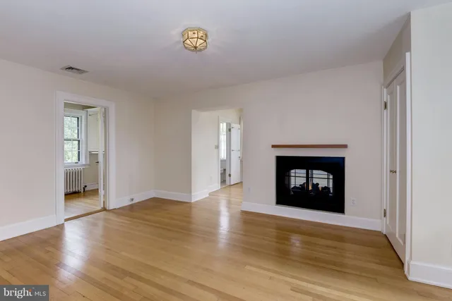 an empty room with wooden floor a fireplace and windows