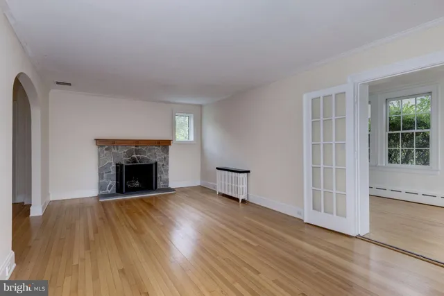 an empty room with wooden floor fireplace and windows