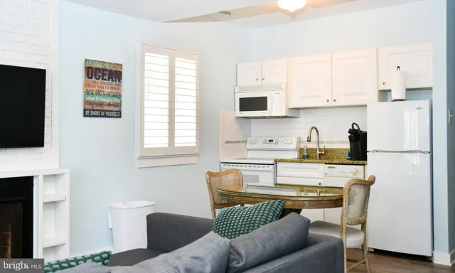 a kitchen with stainless steel appliances a refrigerator a stove a sink a dining table and chairs