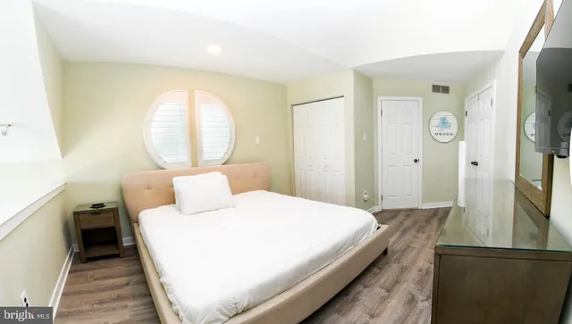 a bedroom with a bed and a large mirror on the dresser