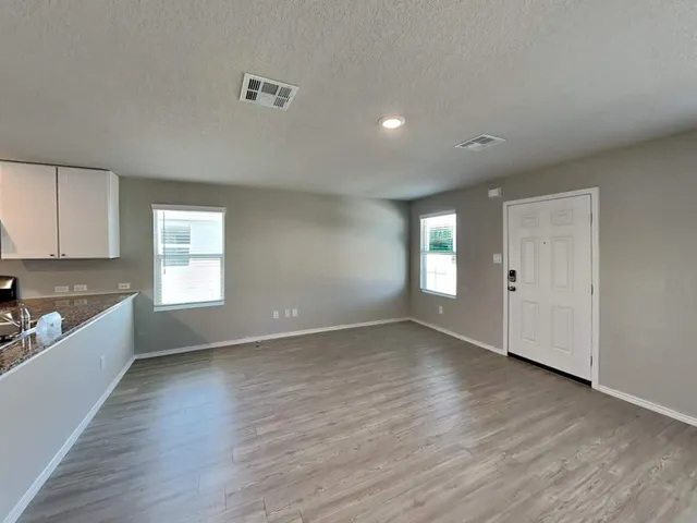 a view of an empty room with window and wooden floor