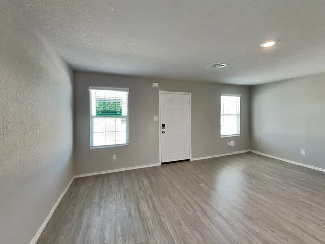 an empty room with wooden floor and windows