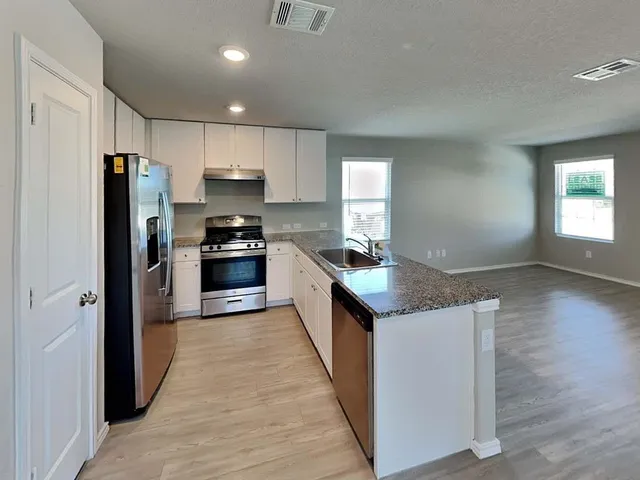 a kitchen with stainless steel appliances granite countertop a refrigerator a stove and a sink