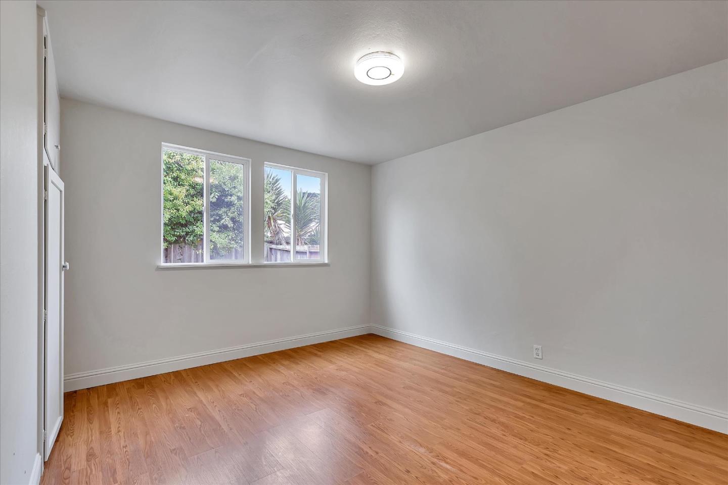 728 Arguello Boulevard Pacifica, CA 94044 - Photo 19 of 34 an empty room with wooden floor and windows