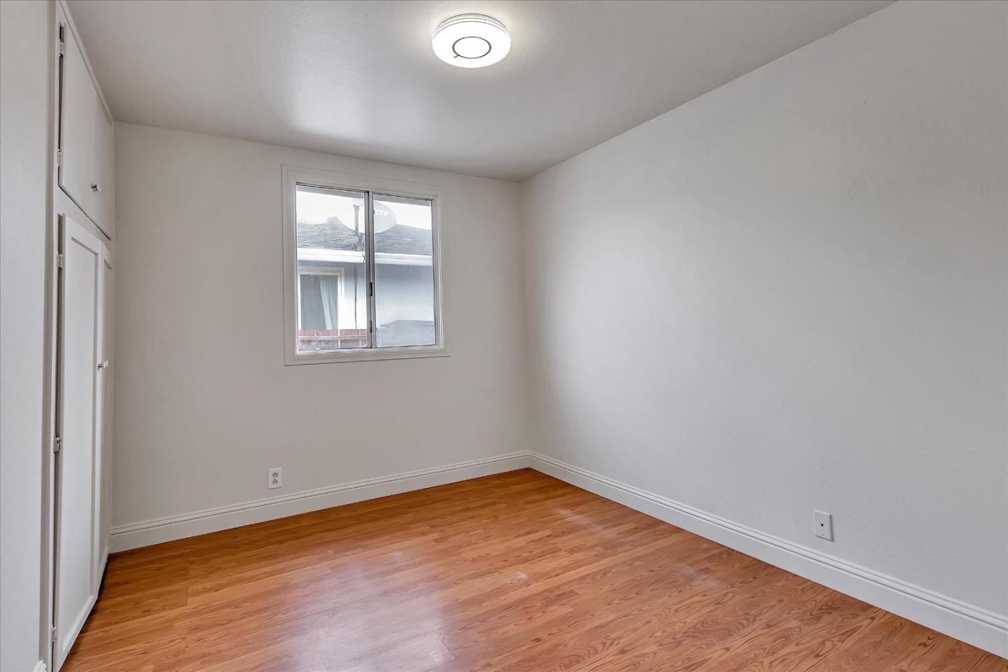 728 Arguello Boulevard Pacifica, CA 94044 - Photo 23 of 34 an empty room with wooden floor and windows