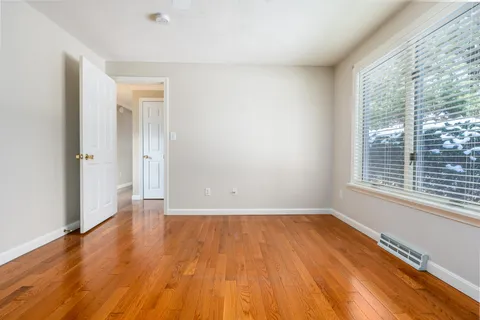 a view of an empty room with wooden floor and a window