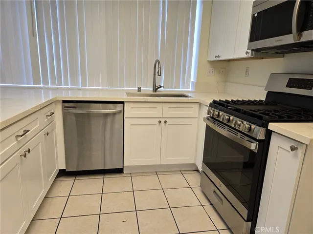 a kitchen with white cabinets a sink dishwasher and a stove with wooden floor